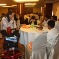 Co-facilitator Nathan (sitting in his mobility scoot) talks with participants at a table during the training. 