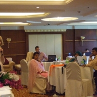 Marcia Rioux stands to the left and points to the camera while participants sit the right during training.