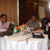 Soy Sokhorn, Prum and Channtey sit at a table and work with training materials. 