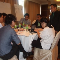 Participants and interpreters gather around a table and work during the training. 