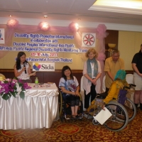 Ashrafun Nahar Misti of Bangladesh holds her certificate in front of facilitators. Lauro shakes her hand in congratulations.