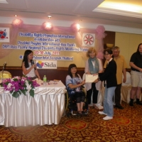 Channtey Heng smiles and holds her certificate with Saowalak Thonkuay while other facilitators look on. 