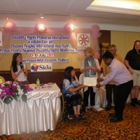 Soy Sokhorn smiles and holds his certificate with Saowalak Thonkuay while other facilitators look on. 