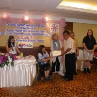 Khamphon Phasayavong smiles holds his certificate with Saowalak Thonkuay while other facilitators look on. 