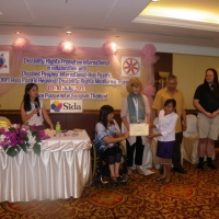 Phoutsady Laoly smiles and holds her certificate with Saowalak Thonkuay and Marcia Rioux while other facilitators look on. 