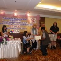 Chintamani Paudel holds his certificate and is congratulated by Saowalak Thonkuay and Marcia Rioux while other facilitators look on. 