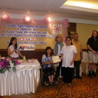 Krongkaew Jindapong smiles while holding her certificate with Saowalak Thonkuay while other facilitators look on. 