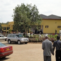 Two men are walking across a parking lot toward a large yellow building.