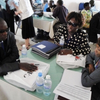 <p>
	A man and two women sit around a circular table with training materials in front of them.</p>
