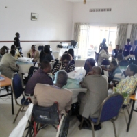 Participants sit separately at three large tables in the training room.