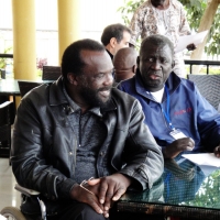 Tambo Camara and Mohamed Fall sit beside each other at a table on a veranda.