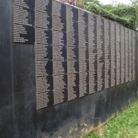 <p>
	A smooth, black stone wall displays many names on plaques</p>

