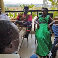 Sam Ntazinda Badege and Mercy Mugure sit on a veranda overlooking the local landscape.
