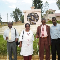 Kennedy Oriko, Amon Anastaz, Magdalina T. Kaihuzi and Felician Mkude stand in front of an outdoor monument marking the genocide in Rwanda.