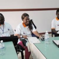 Amon Anastz, Bongi Malope and Felician Mkude sit and look at their certificates. Bongi is smiling.