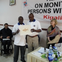 <p>
	Oswald Tuyizere and Severin Rwamucyo hold an artistic print while Marcia looks at them and smiles.</p>
