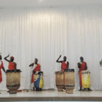 Drummers drum, sing and dance on stage
