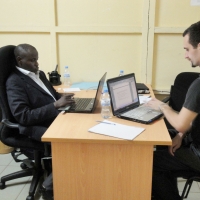 Oswald Tuyizere and Chris Lytle sit on opposite sides of a desk 