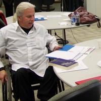 Normand Boucher reads at a round table on his own