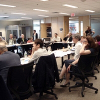 <p>
	Delegates sitting around a conference table, the delegates face each other and listen to a presenter who is outside the frame.</p>
