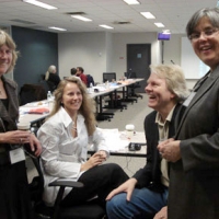 <p>
	Four people are shown at the end of the meeting table, all are laughing while the photo is taken.</p>
