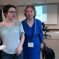 <p>
	Melanie Moore and another participant standing in the meeting room.</p>
