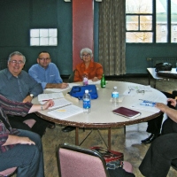 Participants smile while seated around a table littered with training materials and plastic bottles.