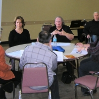 <p>
	Training participants are seated and conversing around a circular table.</p>
