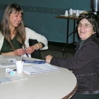 Catherine Fortier and Nathalie Nadeau both smile broadly while seated at a table.