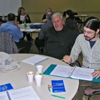 Normand Boucher and Francis Charrier are at a table working with the training materials.