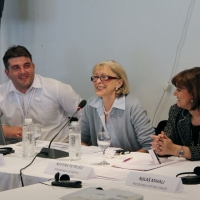 Nevena Petrušić and Radovan Radulović smile while looking at Vesna Petrović who is speaking into a microphone and smiling broadly.