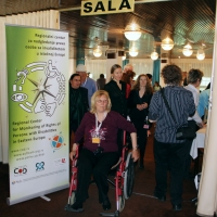 A crowd of people are close to the entrance to the training room. A large banner is located next to the entrance which reads 'Regional Center for Monitoring the Rights of Disabilities in Eastern Europe'.