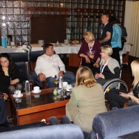 Seven training participants sit in comfortable chairs arranged around a coffee table and talk.