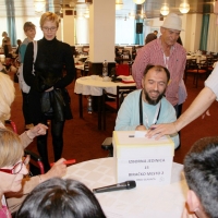 Participants gather around a table with an election box on it. Chris Lytle is placing a piece of paper in the box.