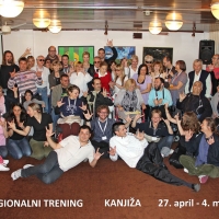 Participants stand and sit close together and smile for a group photo in the training room.