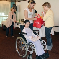 Miroslava Mima Ivanović holds a certificate and smiles broadly while Bojana and Marina Mitrović exchange a red bag with the York University logo on it. Marcia Rioux is in the background.