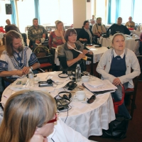 Participants are gathered around small round tables covered with training materials during the training.