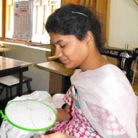 <p>A female trainee at the National Institute for the Mentally Handicapped sits while working on embroidery.</p>
