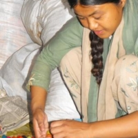 <p>Woman from Entire Power in Social Action crouching down working on crafts</p>
