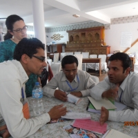 <p>
	Ram and Rita are to the left of two participants that are seated during the training. Ram is leaning over the table to make a point during the discussion.</p>
