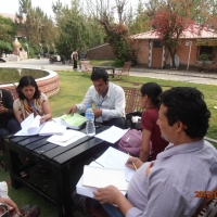 A group of participants sit in chairs in front of an ornamental pond and review their training manuals. 