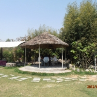 <p>
	Four participants sit underneath a woven grass roof outside in the hotel garden.</p>
