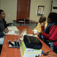 Thozama Marasi, Muzi Nkosi and Donecia Mokoena sit at a table in the conference room.