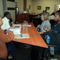 Vanessa dos Santos, Betty Masipa, Phumza Sikumba and Judith Madi  are sitting in the training room at a big table. 