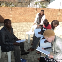 Oswald Tuyizere, Makhi Mfengu, Mnikelwa Nompilwane, Pumla Dyodyo are sitting outside of the training venue. 