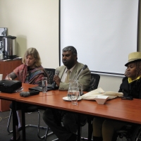 From left to right: Prof. Marcia Rioux, Jair Nair and Bongiwe Malope are sitting at a table in front of a white screen. 