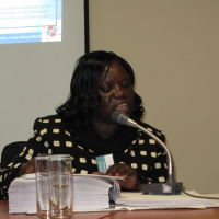 Roseweter Mudarikwa at the table with microphone, facilitating the session using brailled materials.