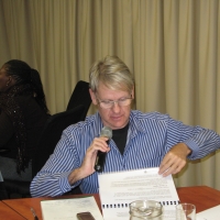 Fanie Swangpogl holds a microphone using his large-printed materials to ask a question in the training venue.