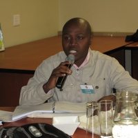 <p>
	Surprise Mokgope is sitting at a table with a microphone giving his comments during the session.</p>
