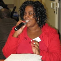 Zama Ngwenya holds a microphone at a table